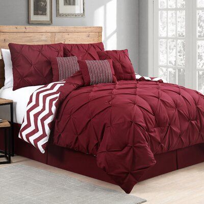 a bed with red comforter and pillows on it