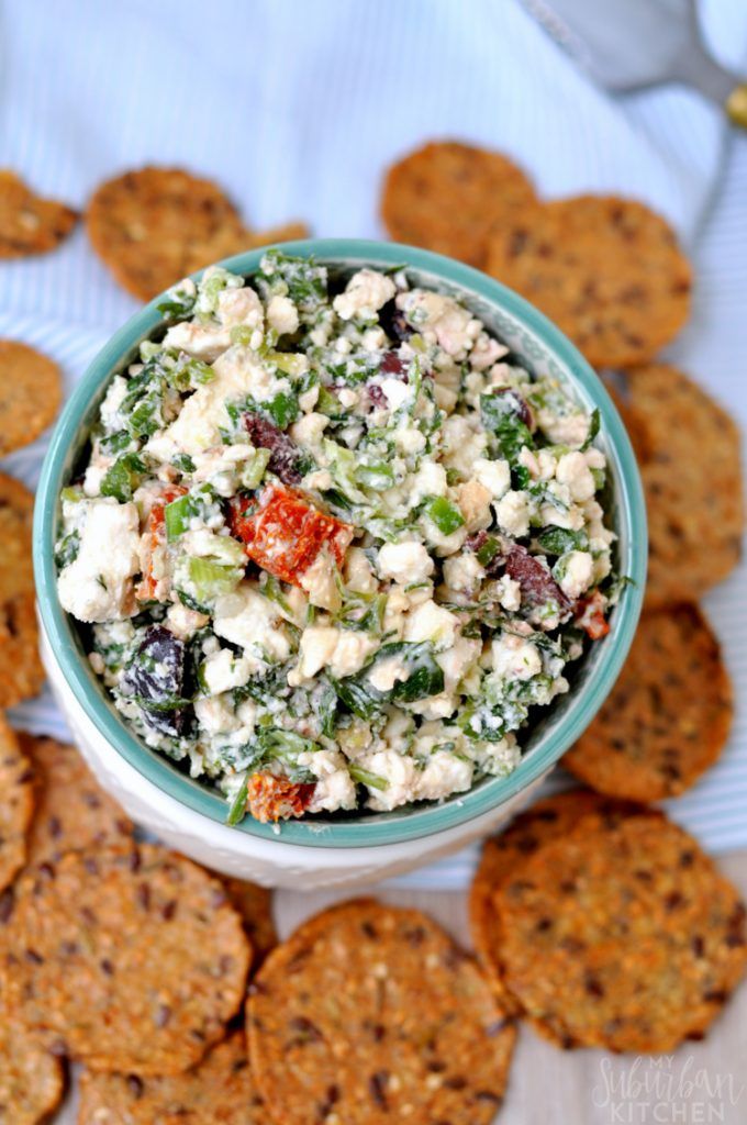 a bowl filled with salad next to crackers