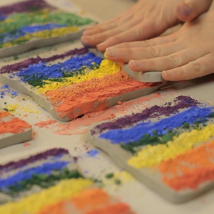 someone is making colorful art with crayons and colored sand on the table in front of them