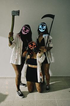 three women with masks on their faces holding axes