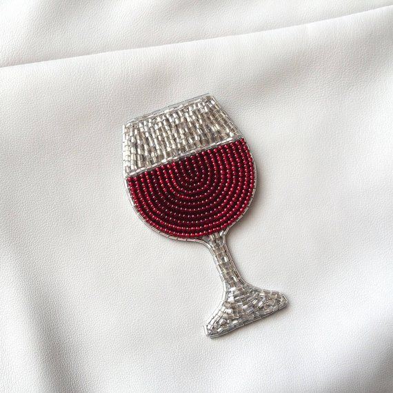 a red beaded wine glass sitting on top of a white cloth