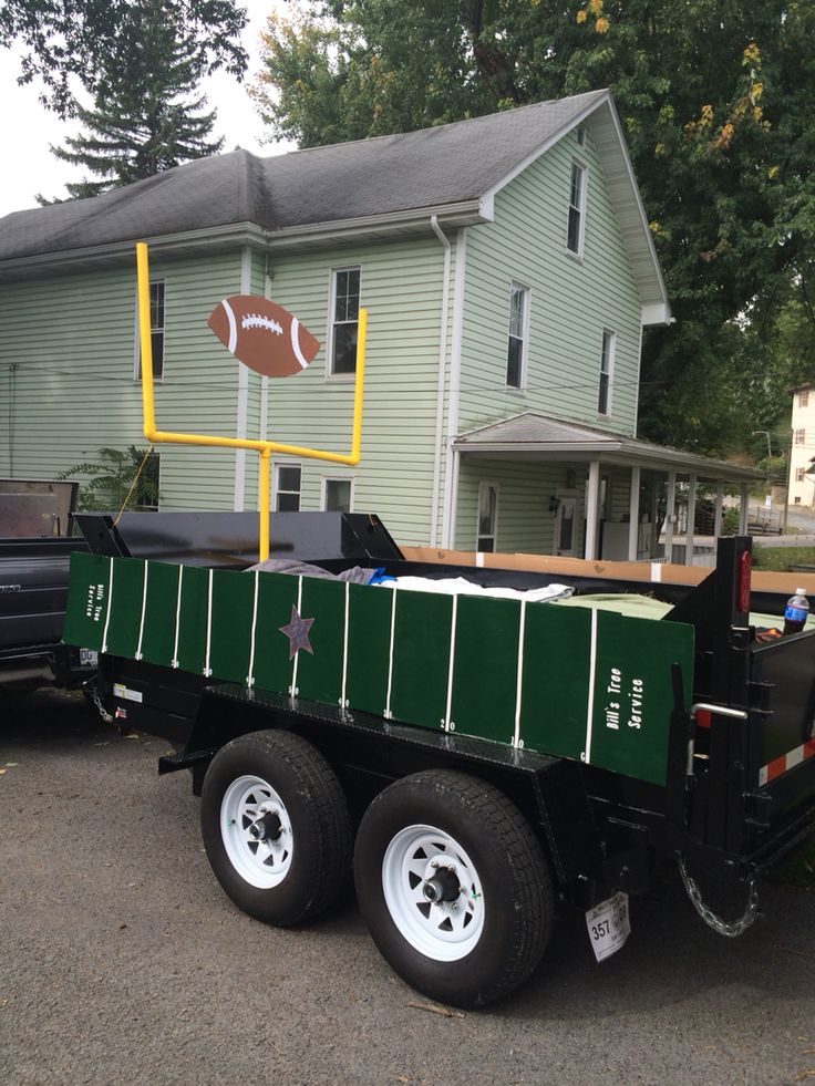 a large green trailer parked in front of a house with a football sign on it