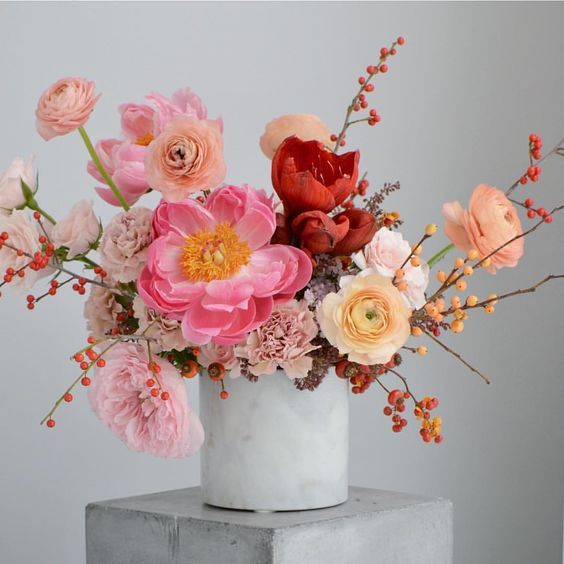 a white vase filled with lots of pink and orange flowers