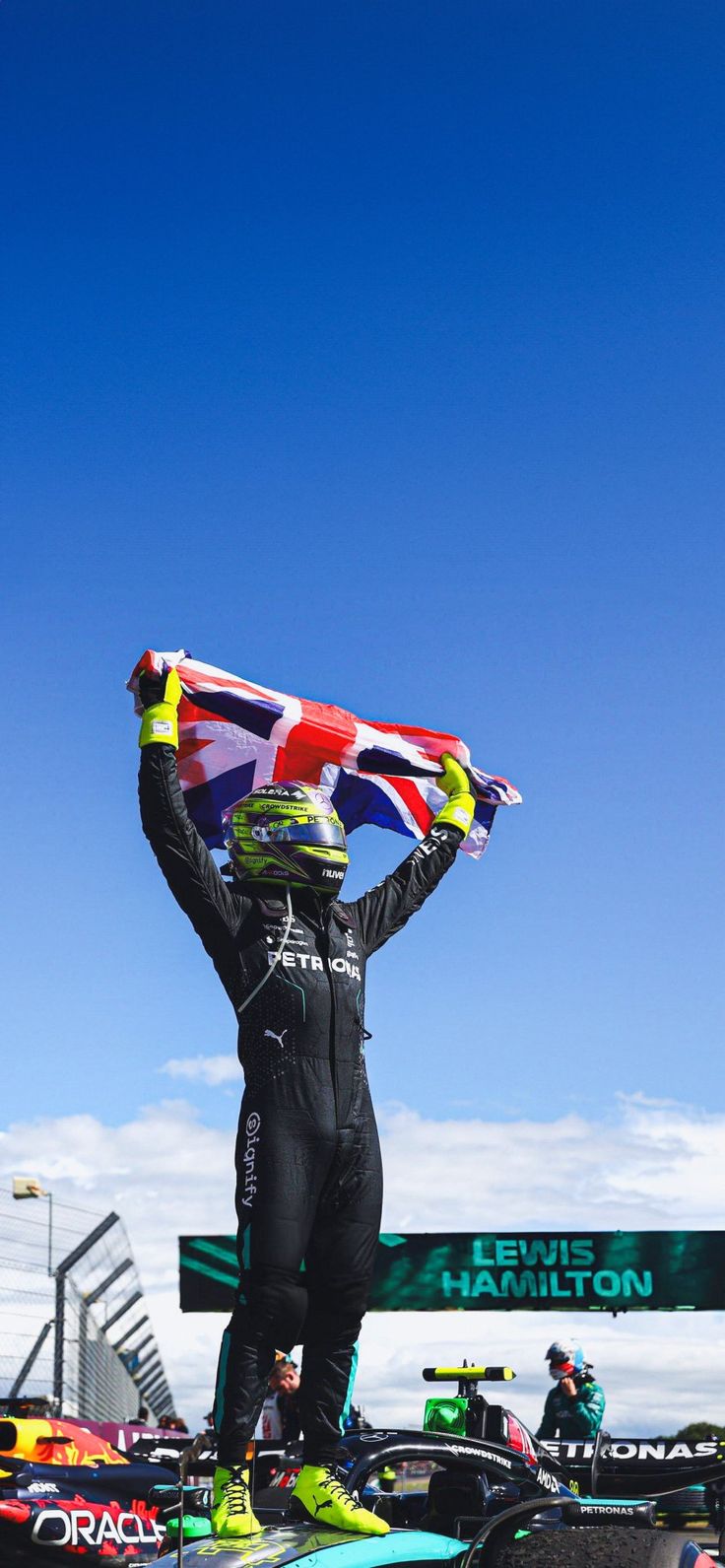 a man standing on top of a race car holding up a flag in the air