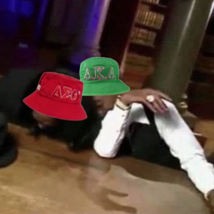 two hats sitting on top of a wooden table next to each other in front of a book shelf