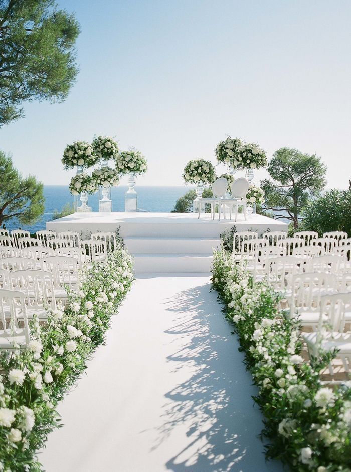 an outdoor wedding setup with white flowers and greenery at the end of the aisle