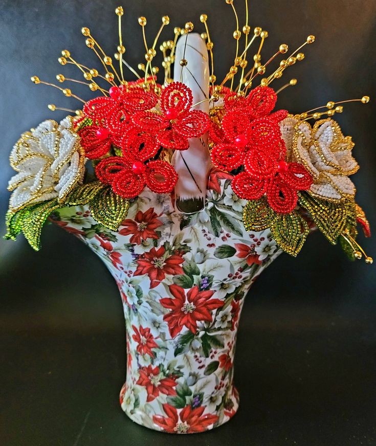 a vase filled with red and white flowers on top of a black table next to a candle