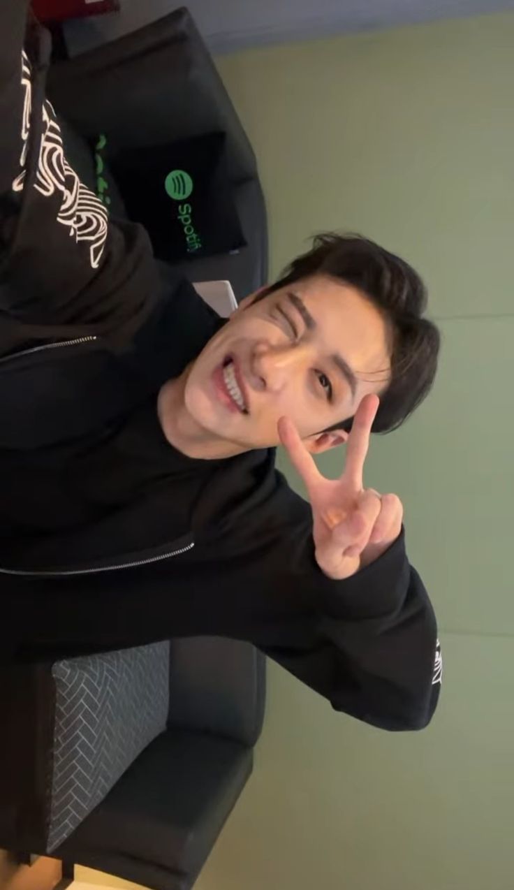 a young man making the peace sign with his hand while sitting in an office chair