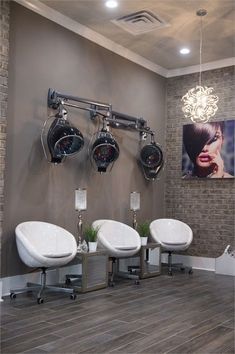 the interior of a hair salon with three chairs and two lights hanging from the ceiling