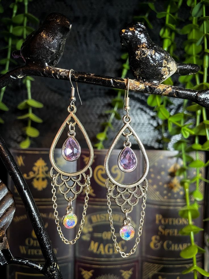 ️ PURPLE MERMAID SCALE EARRINGS ️ The Purple Mermaid Scale Earrings feature a silver metal scalloped design with iridescent purple glass charms and chain accents. * MATERIALS * Each piece at Nighthawk Jewelry is made up of a combination of materials, including: - Stainless Steel - Silver-plated metal - Gold-plated metal - Rose gold-plated metal - Rhodium - Iron - Brass - Assorted crystals (some items may differ in appearance due to natural variations) Disclaimer: Because every piece is made of a Purple Crystal Metal Earrings For Party, Purple Metal Drop Earrings, Purple Metal Dangle Earrings, Mystical Nickel-free Teardrop Jewelry, Purple Dangle Metal Earrings, Mystical Teardrop Nickel-free Jewelry, Iridescent Metal Dangle Jewelry, Iridescent Pierced Jewelry For Party, Purple Nickel-free Teardrop Dangle Earrings