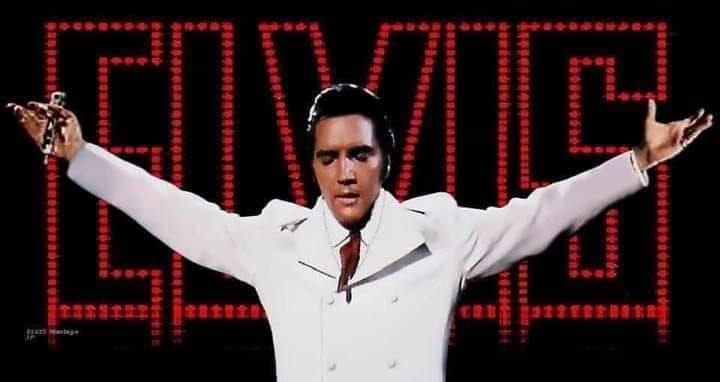 elvis presley standing in front of a sign with his arms outstretched and hands out to the side