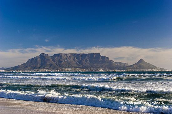 the ocean and mountains are in the distance with waves coming up on it's shore