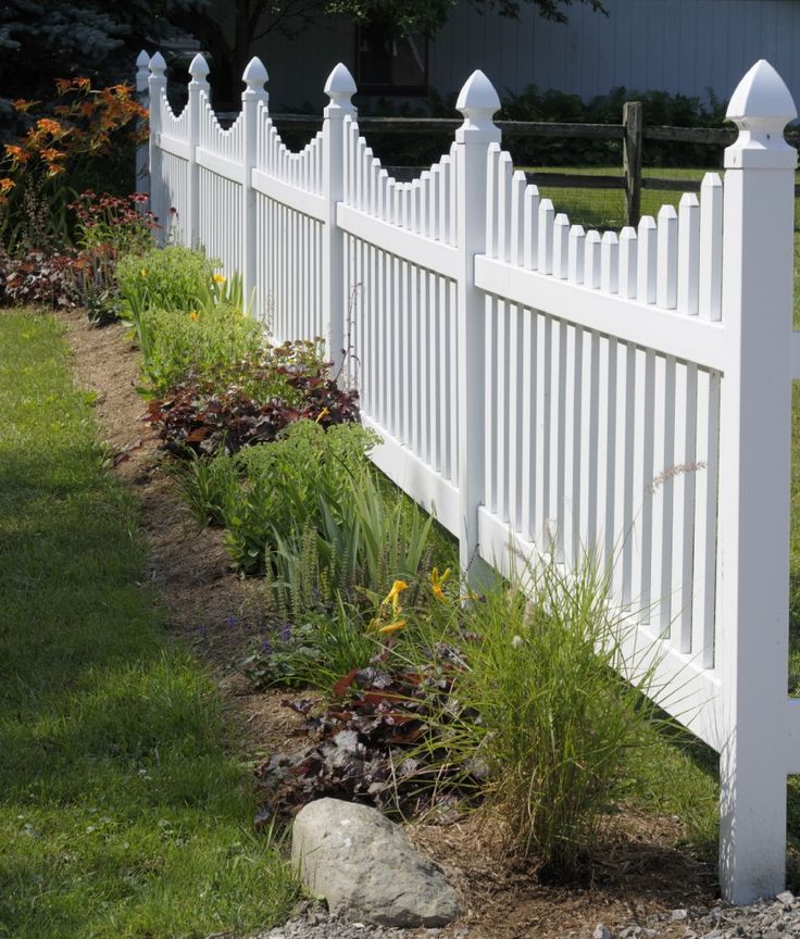 a white picket fence surrounded by flowers and rocks