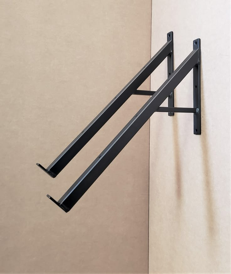 two black metal brackets mounted to the side of a wall next to a beige wall