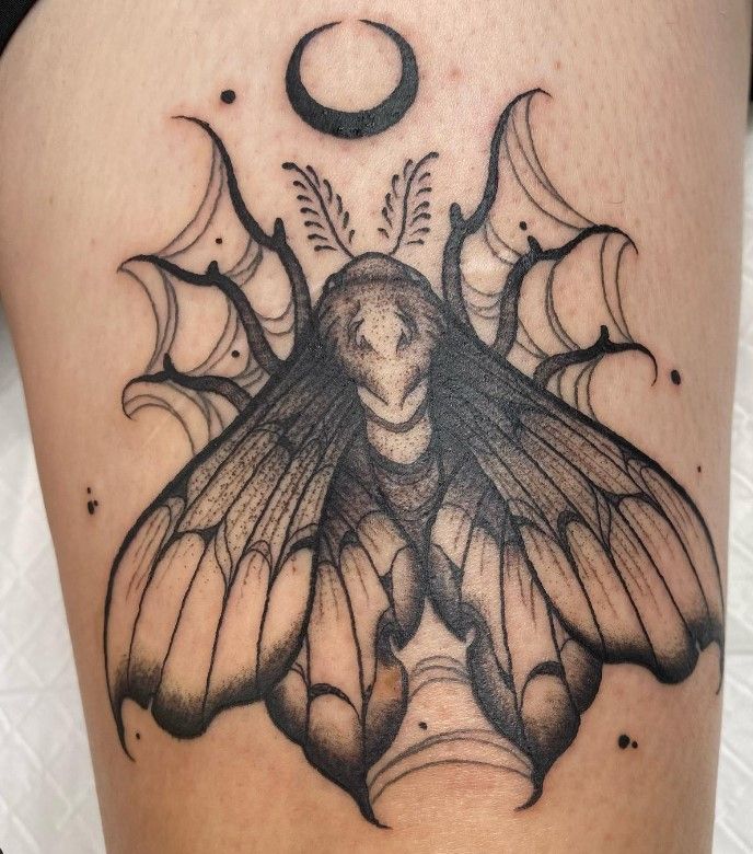 a woman's thigh with a black and white tattoo design on her leg that has a butterfly in the middle