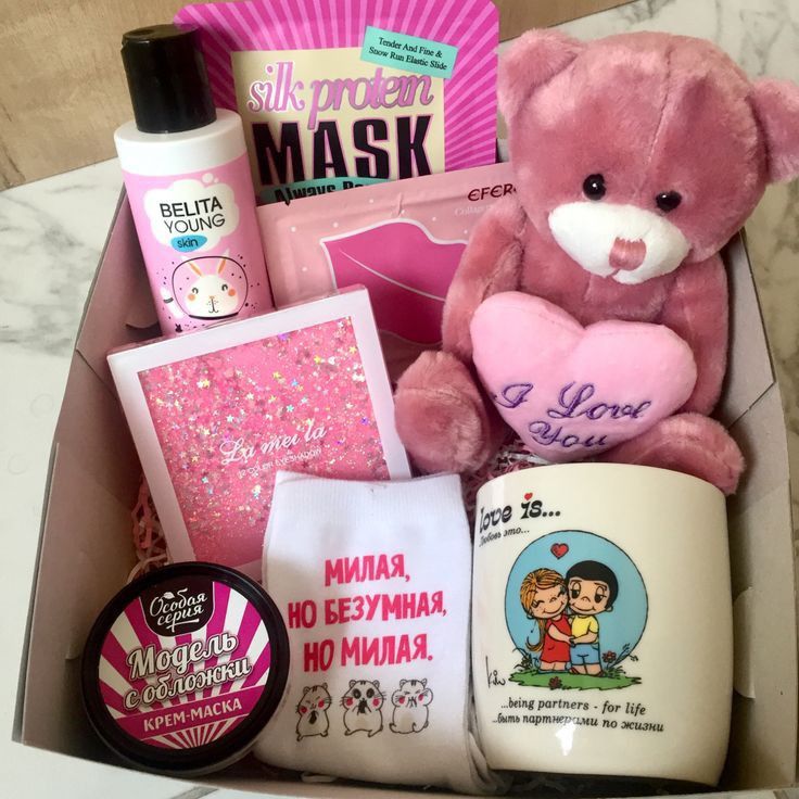 a pink teddy bear sitting inside of a box filled with personal care products and other items