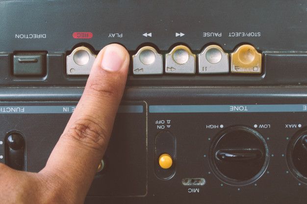 a hand is pressing the buttons on an old radio receiver with other electronic equipment in the background