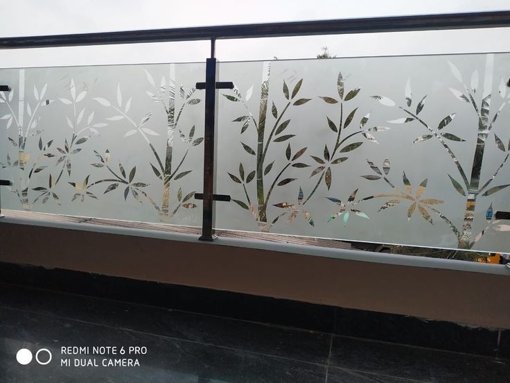 a glass window with flowers etched on the glass and behind it is a metal rail