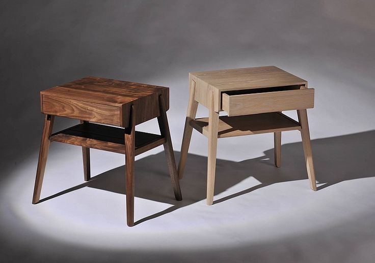 two small wooden tables sitting next to each other on a white surface with shadows from the floor