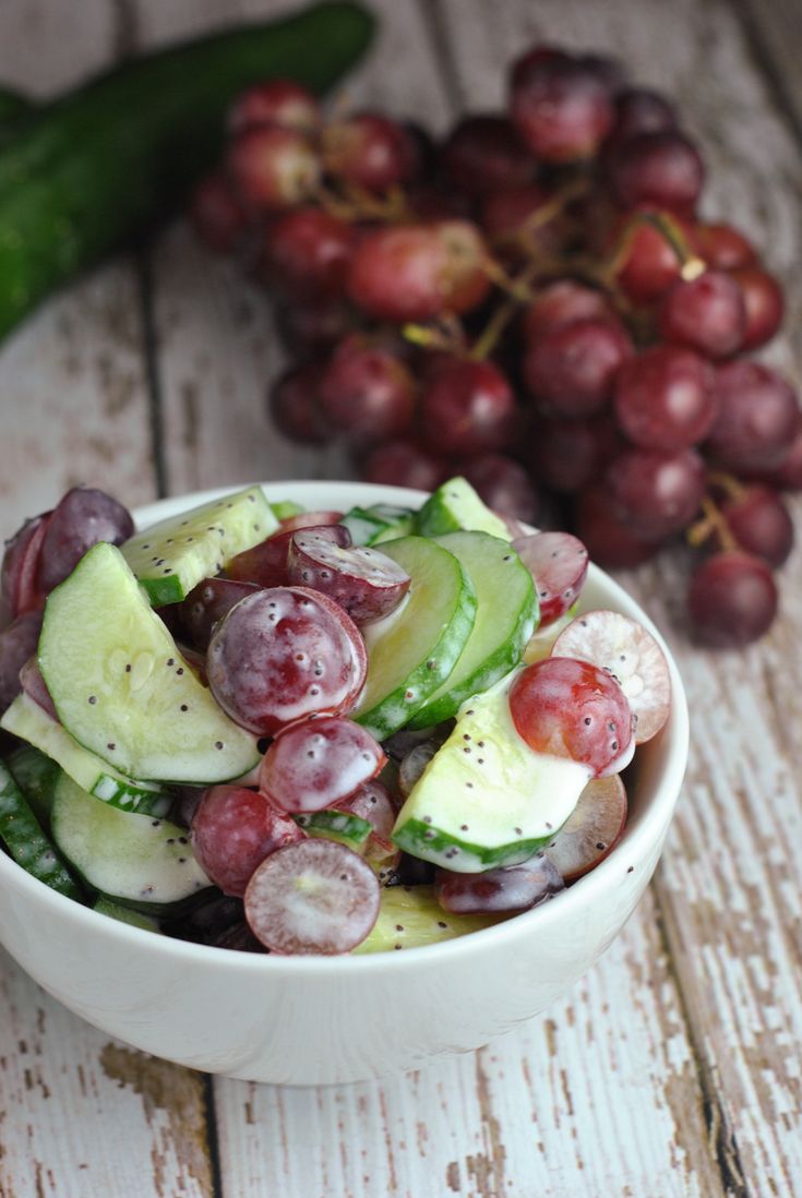 a white bowl filled with grapes and cucumbers