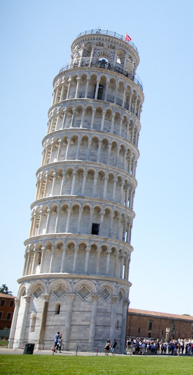 the leaning tower has people standing around it