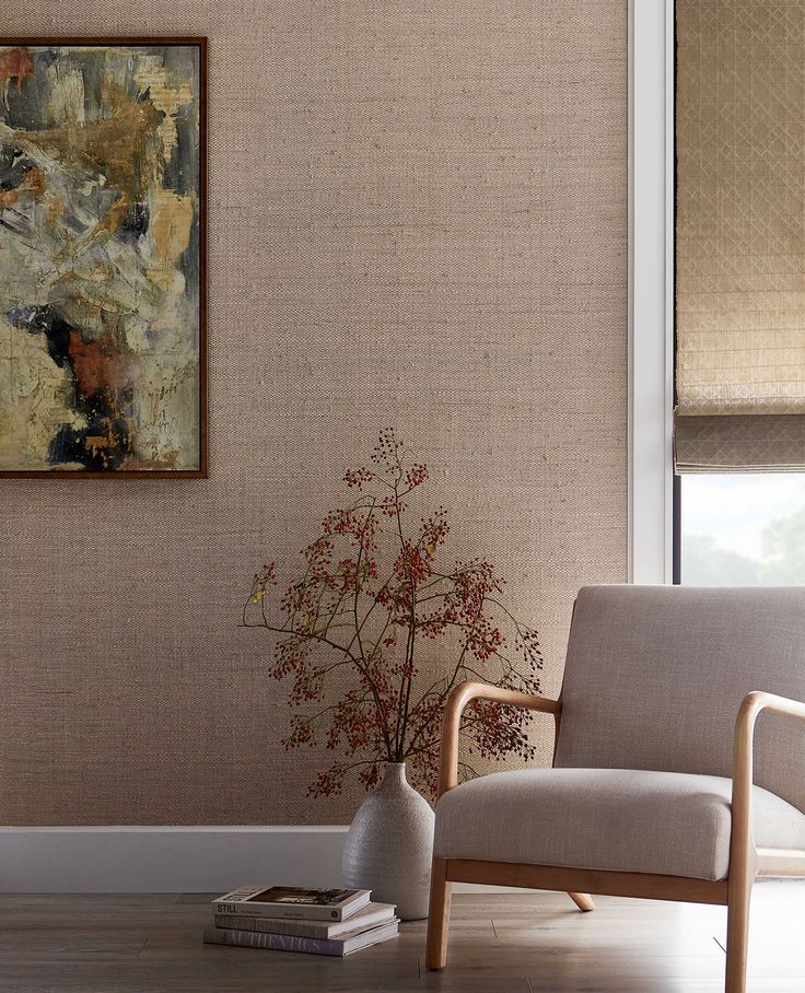 a living room scene with focus on the chair and wall coverings, along with a vase filled with flowers