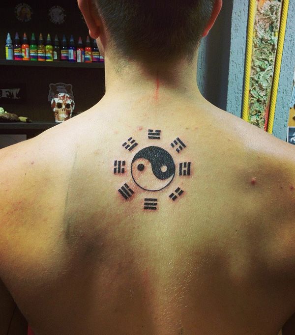 a man with a tattoo on his back has a yin - yang symbol in the center