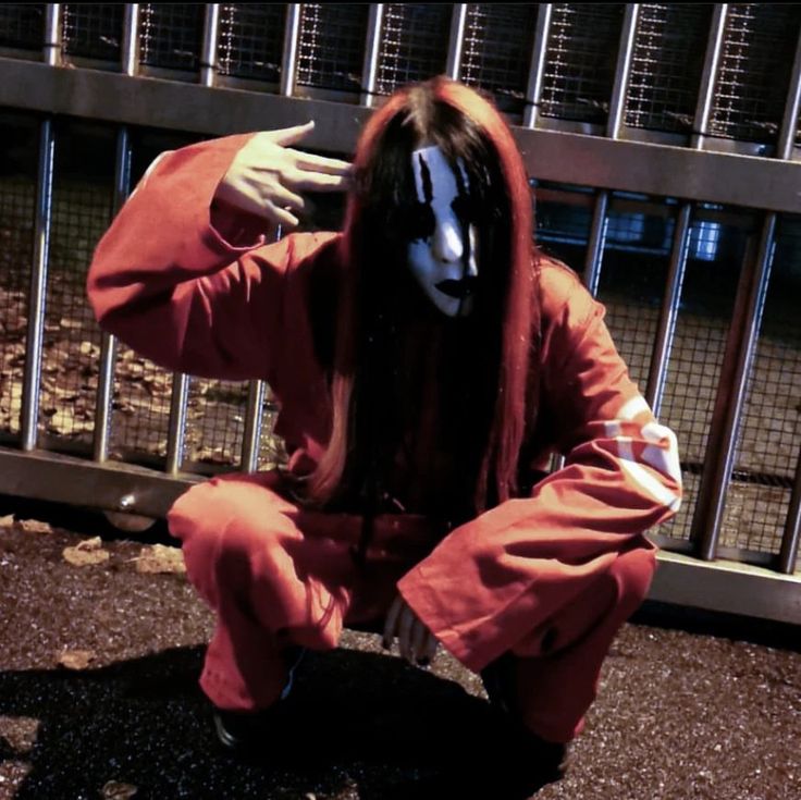 a person in a red outfit sitting on the ground with their hands behind his head