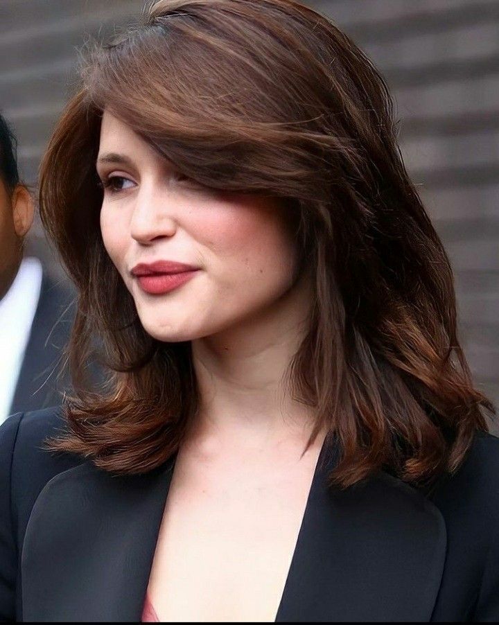 a close up of a person wearing a suit and tie with one hand on her hip