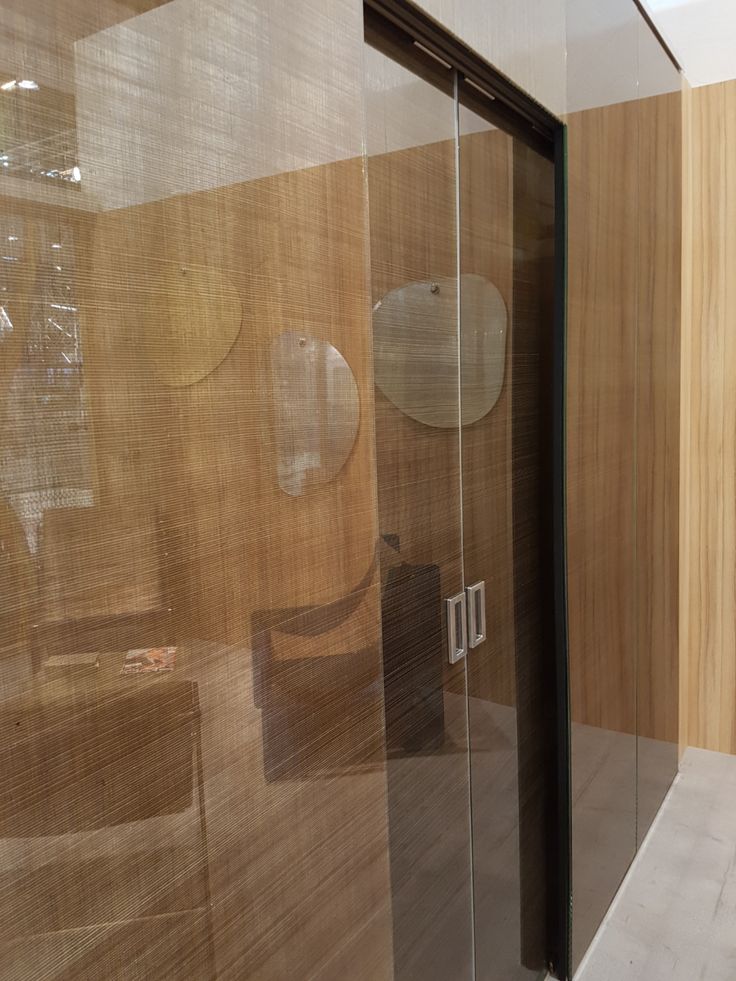 a glass shower door in a bathroom with wooden walls