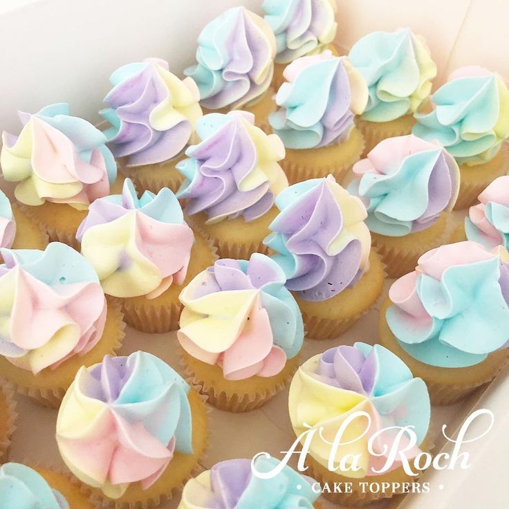 a box filled with cupcakes covered in pastel frosting and ruffled icing