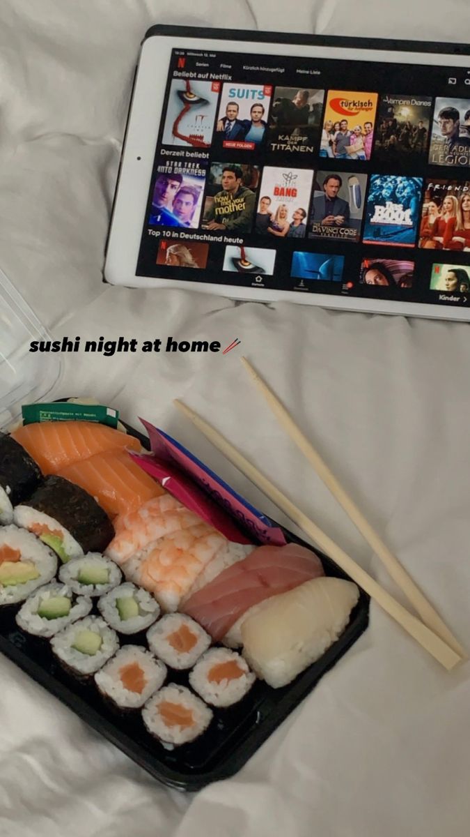 sushi and chopsticks sit on a bed next to an ipad with the caption'sushi night at home '