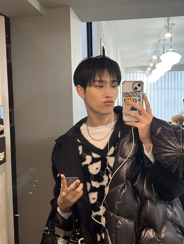 a young man taking a selfie in front of a mirror with his cell phone