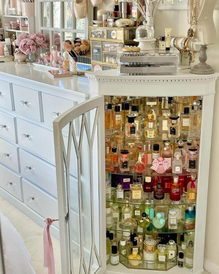 a white cabinet filled with lots of bottles and jars on top of a counter next to a dresser