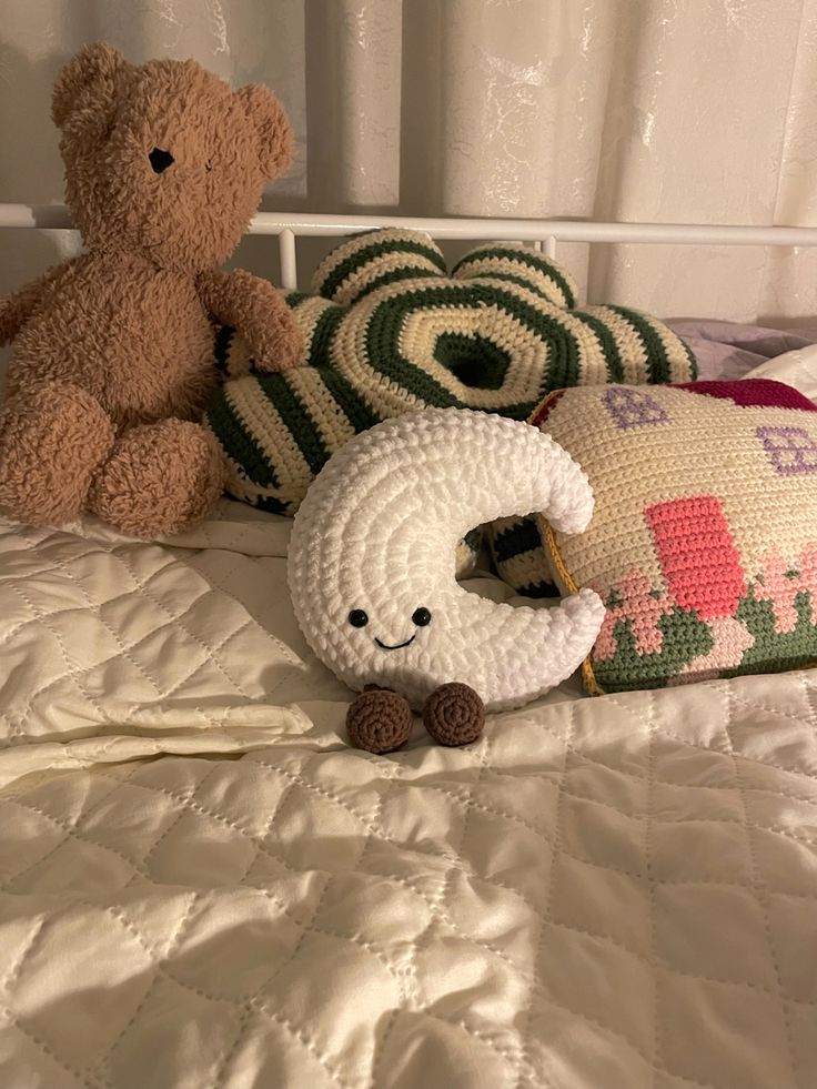 two stuffed animals sitting on top of a bed next to pillows and pillow cases,