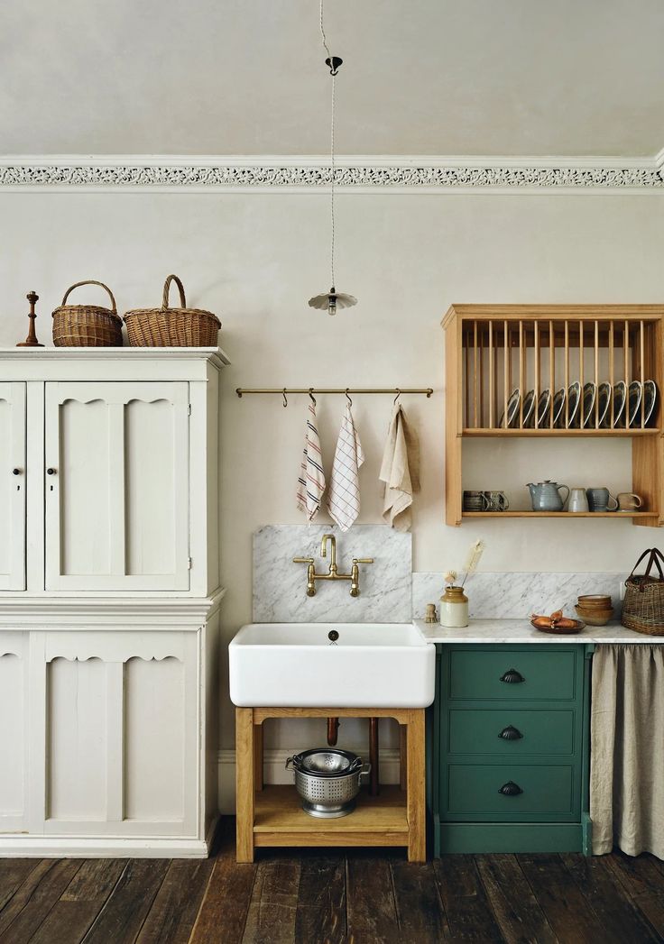 a kitchen with wooden floors and white walls, green cabinets and an old fashioned sink