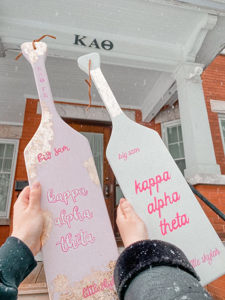 two people holding up signs in front of a building with snow falling on the ground