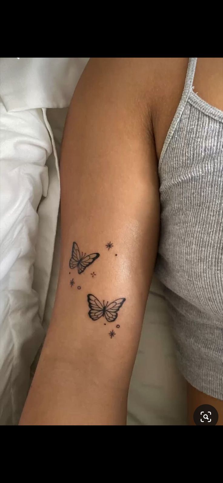 a woman's arm with two butterflies on it and stars in the sky above her