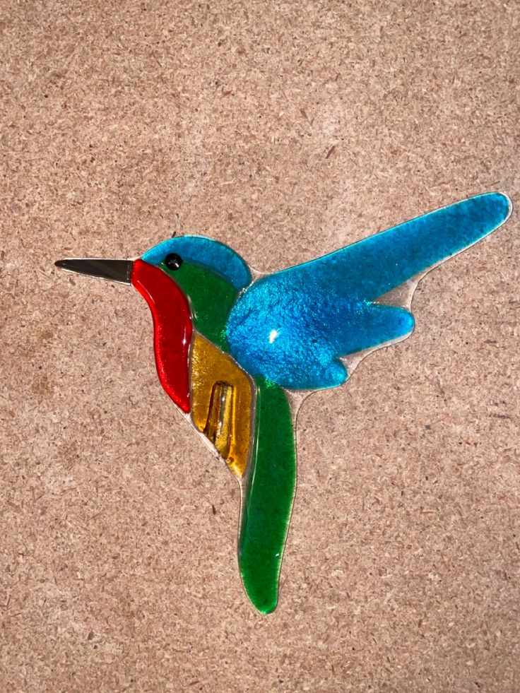 a colorful glass bird sitting on the ground