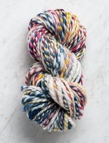 two skeins of multicolored yarn on a marble surface