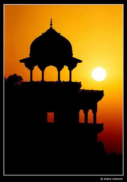 the sun is setting behind an ornate building