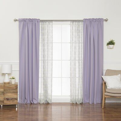 a living room filled with furniture and a window covered in purple drapes, sitting next to a wooden dresser