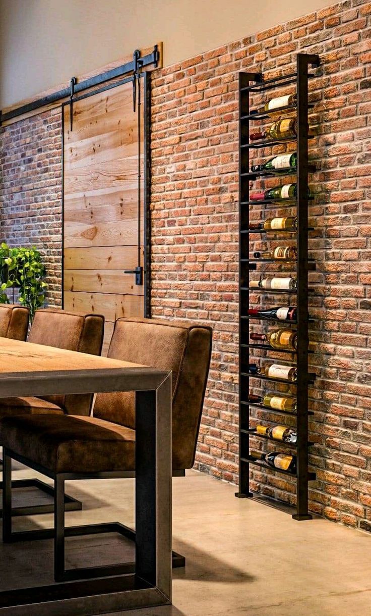 a dining room table and chairs with wine bottles on the wall in the back ground