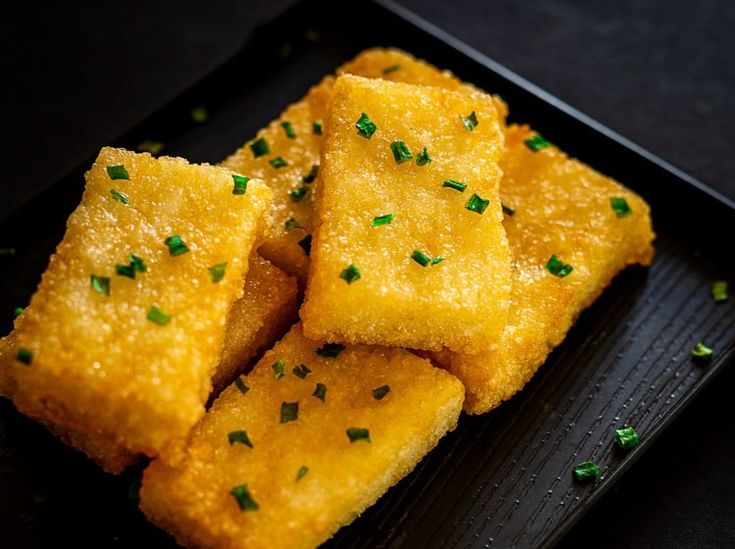 some food that is sitting on a black plate with green sprinkles around it