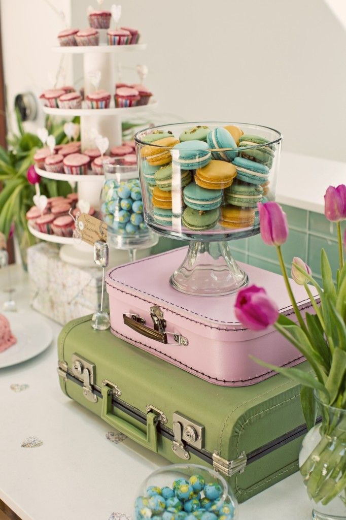 an assortment of desserts and pastries are displayed on a table with green suitcases