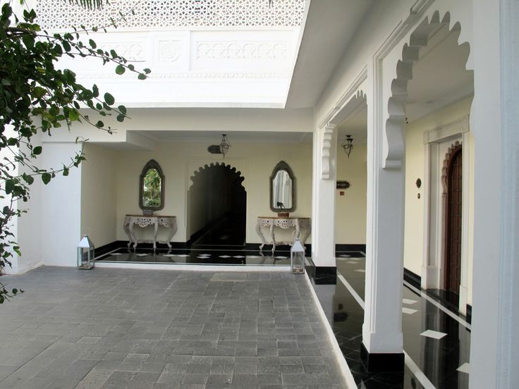 an indoor area with black and white tile flooring, arched doorways and mirrors on the wall