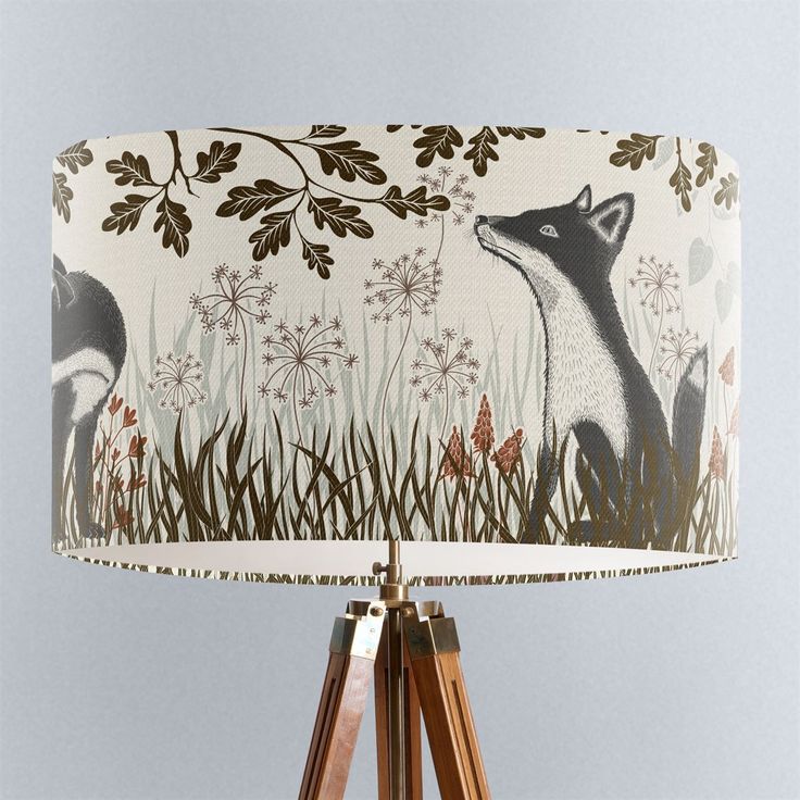 a lamp shade with an image of a fox on it's side and flowers in the background