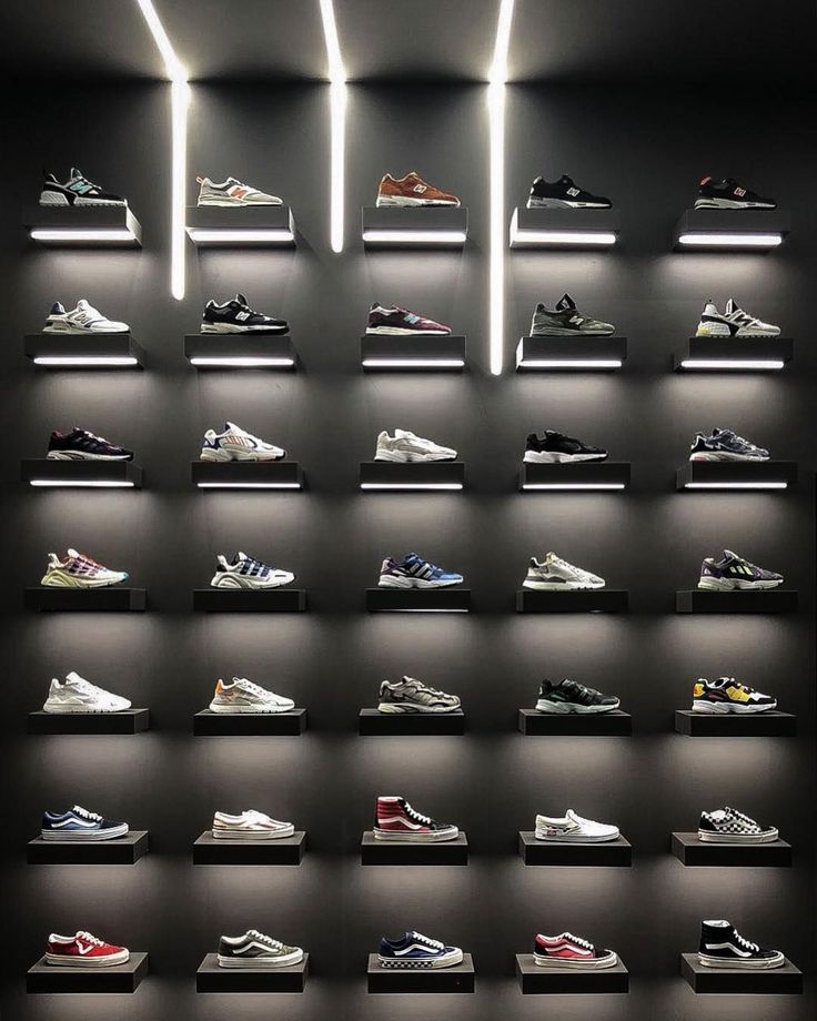 a display case with many pairs of shoes on the shelves in front of it, all lit up by neon lights