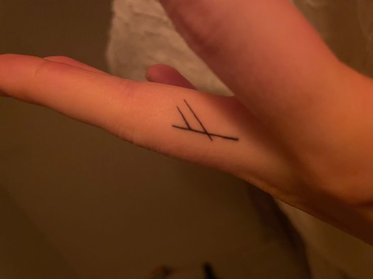 a person with a small tattoo on their left hand and two crossed sticks in the middle