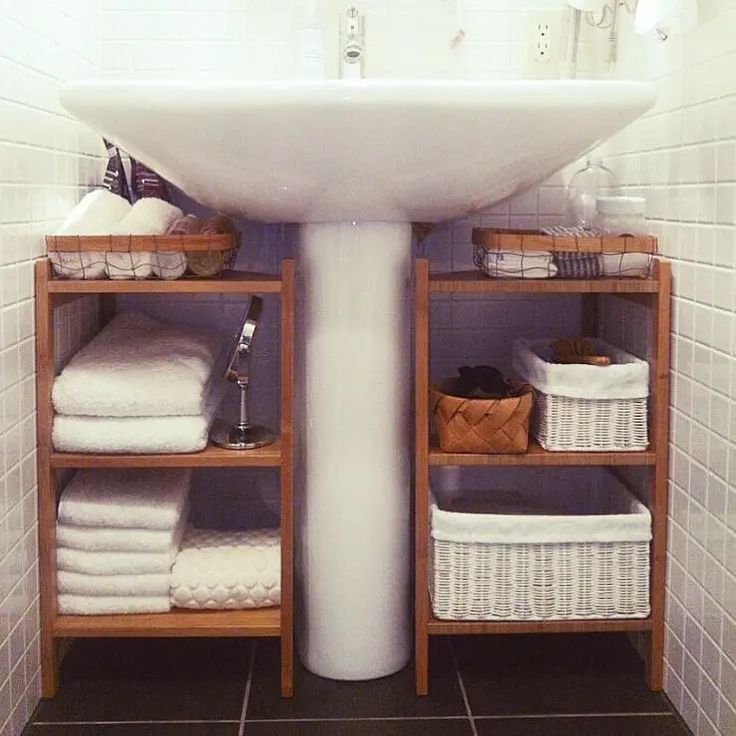 a white sink sitting under a bathroom mirror next to a shelf with baskets on it